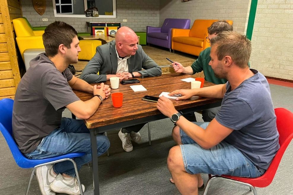 Een groep leiders zitten aan tafel en werken samen aan een opdracht.