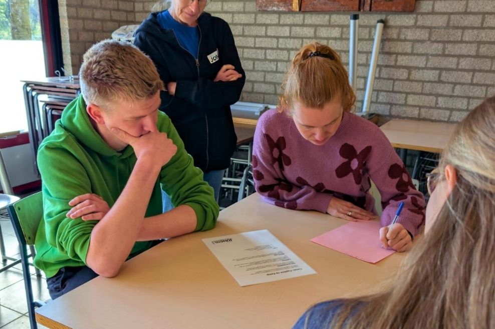 Een groepje leiders werkt samen een opdracht uit op papier.
