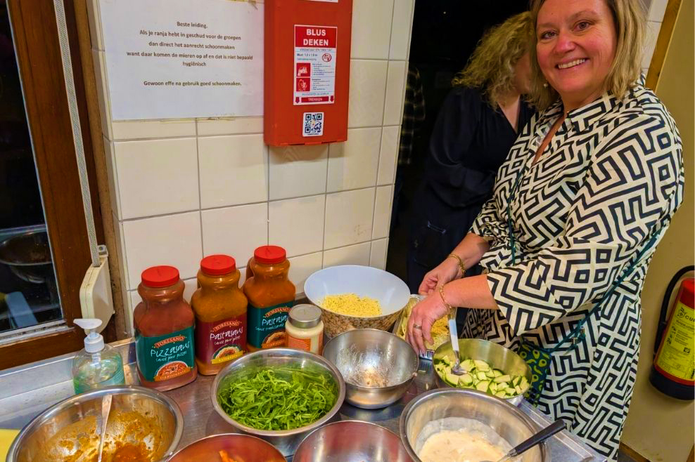 Een vrijwilliger helpt met het bereiden van de pizza's.