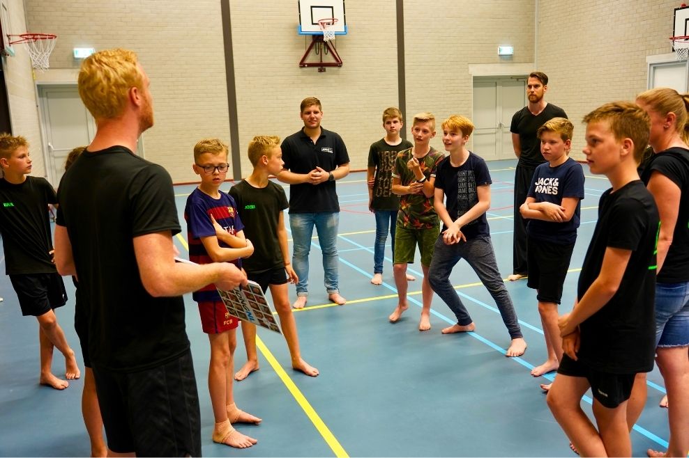 Een groep leden leert tijdens een workshop alles over vechtsport.