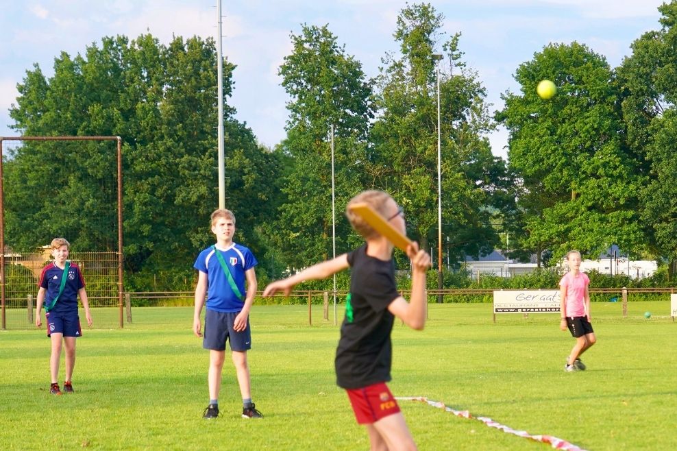 Een groep jongens speelt samen slagbal.
