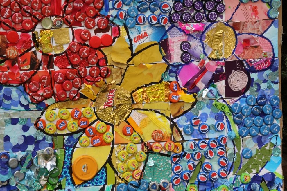 Een kunstwerk wat samen door kinderen is gemaakt met behulp van bierdopjes en verpakkingen.