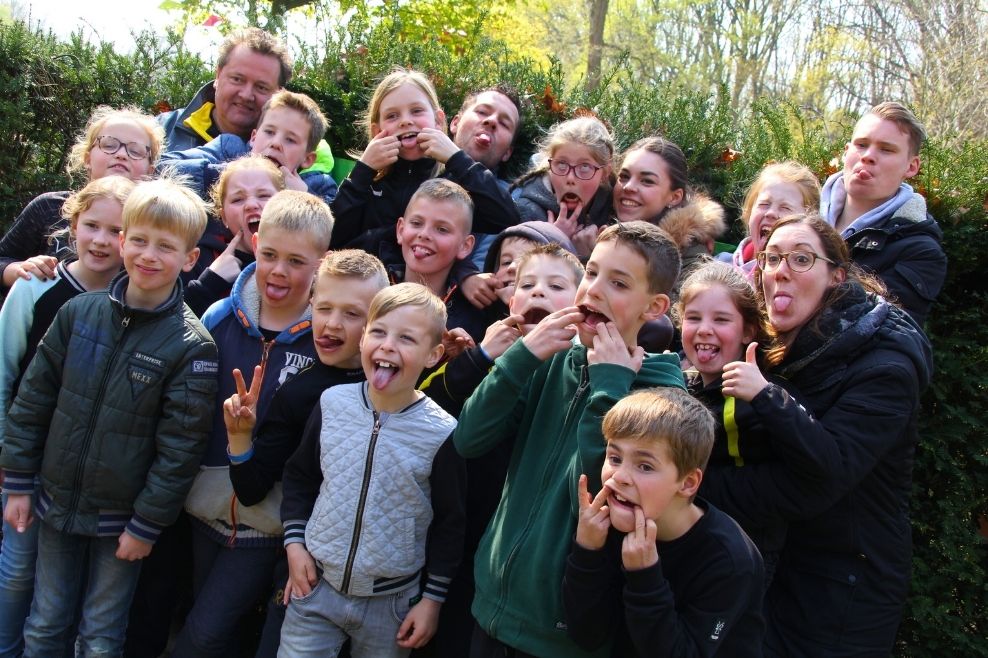 Een groepsfoto van kinderen en leiding die een gekke bek trekken.
