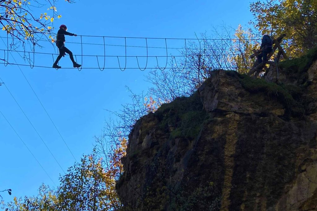 Een kind loopt over een touwbrug op hoogte.