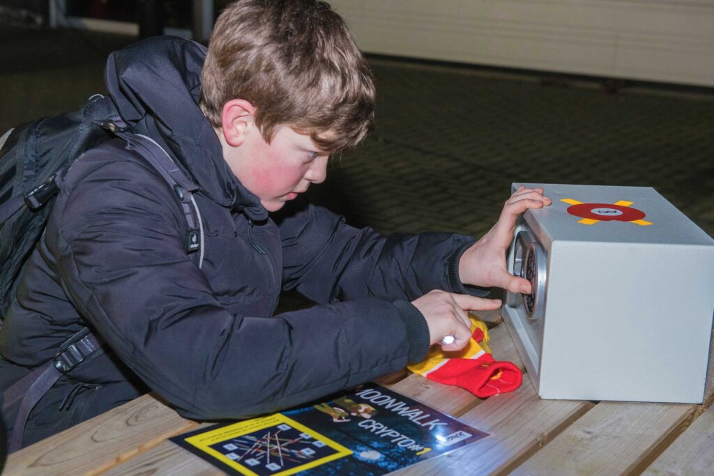 Een jongen probeert een puzzel te ontcijferen en een kluis te openen.