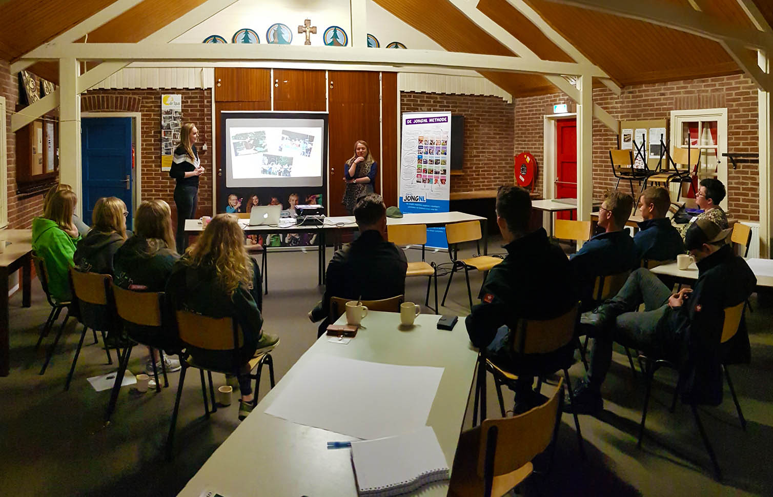 Een groep leiding luisteren zittend naar de workshopleiders.