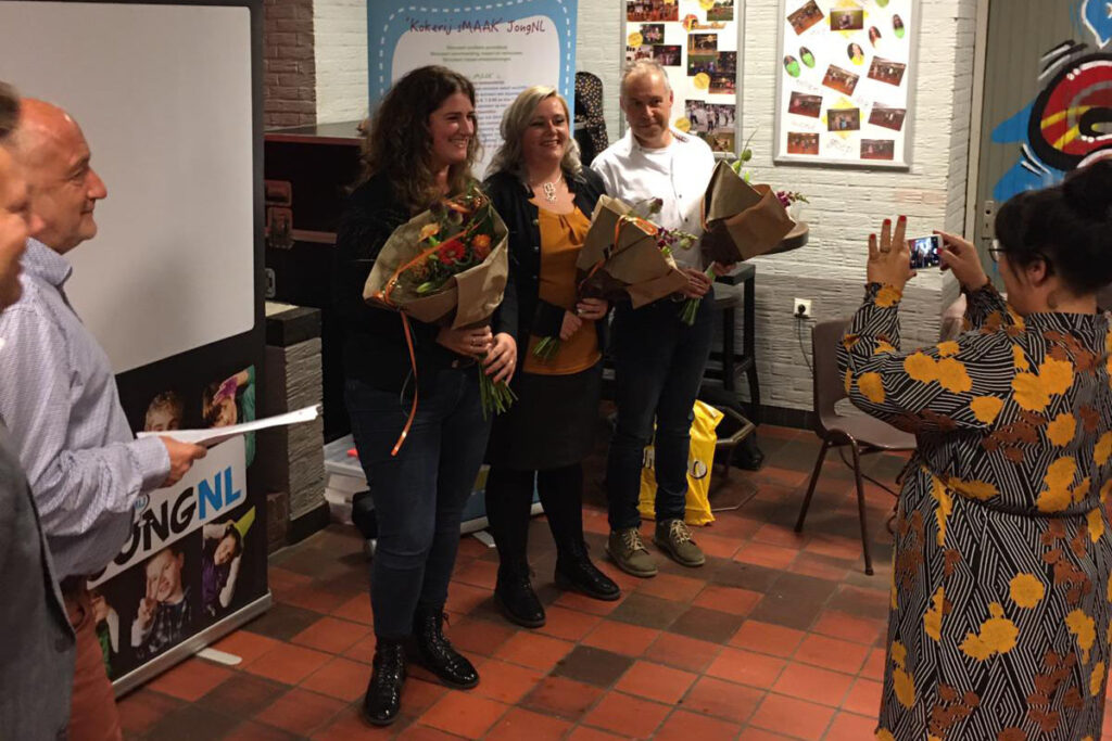 Drie bestuursleden worden verrast met een bloemetje.