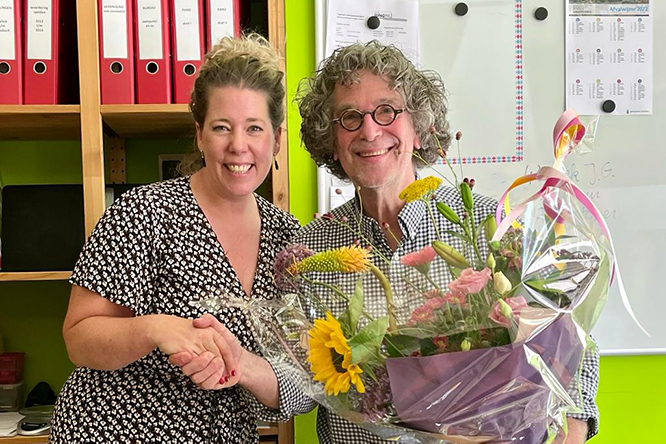 Een bureauteam medewerker neemt een bos bloemen in ontvangst van de coördinator.