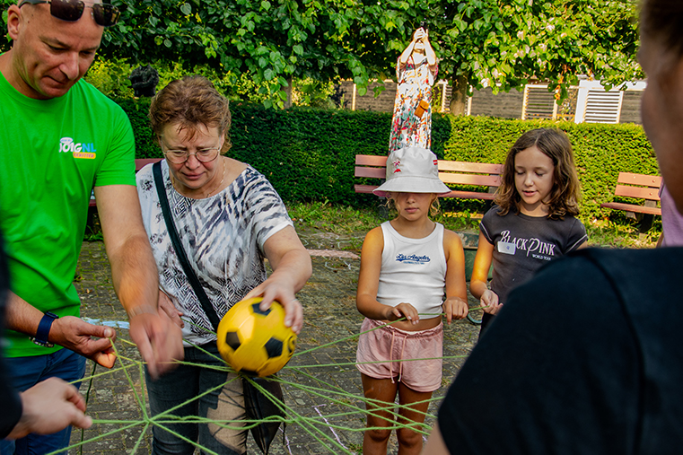 Een groep kinderen en leiding spelen een spel met touw en een bal.
