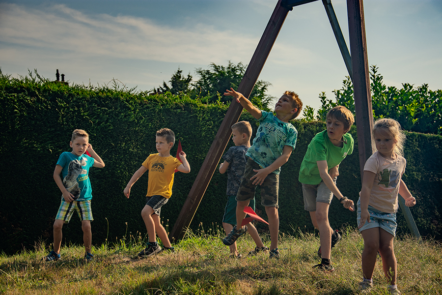 Een groep kinderen gooit zelf gevouwen vliegtuigen van papier.