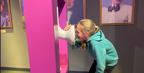 Een meisje praat in een praatpaal in het museum.