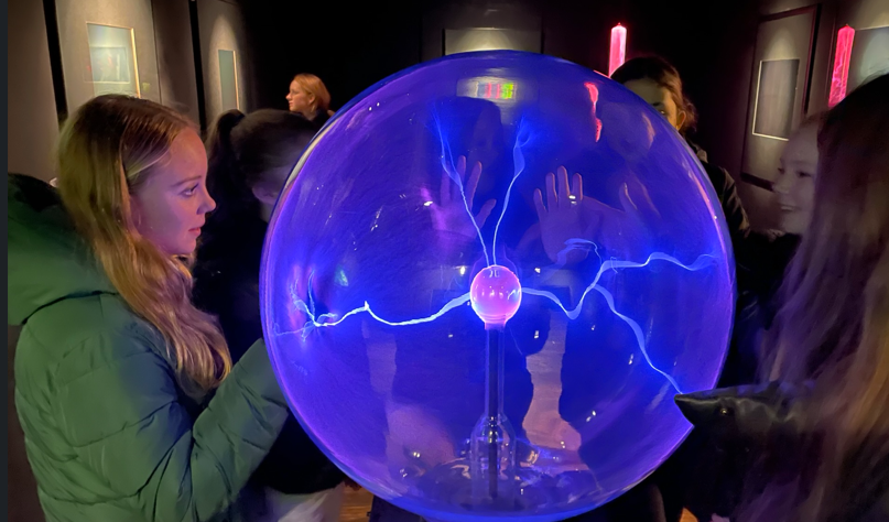 Een groep leden raken een plasmabol aan in het museum.