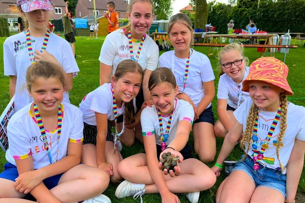 Groep leden van JongNL lachen naar de camera en houden een handjevol slakken vast.