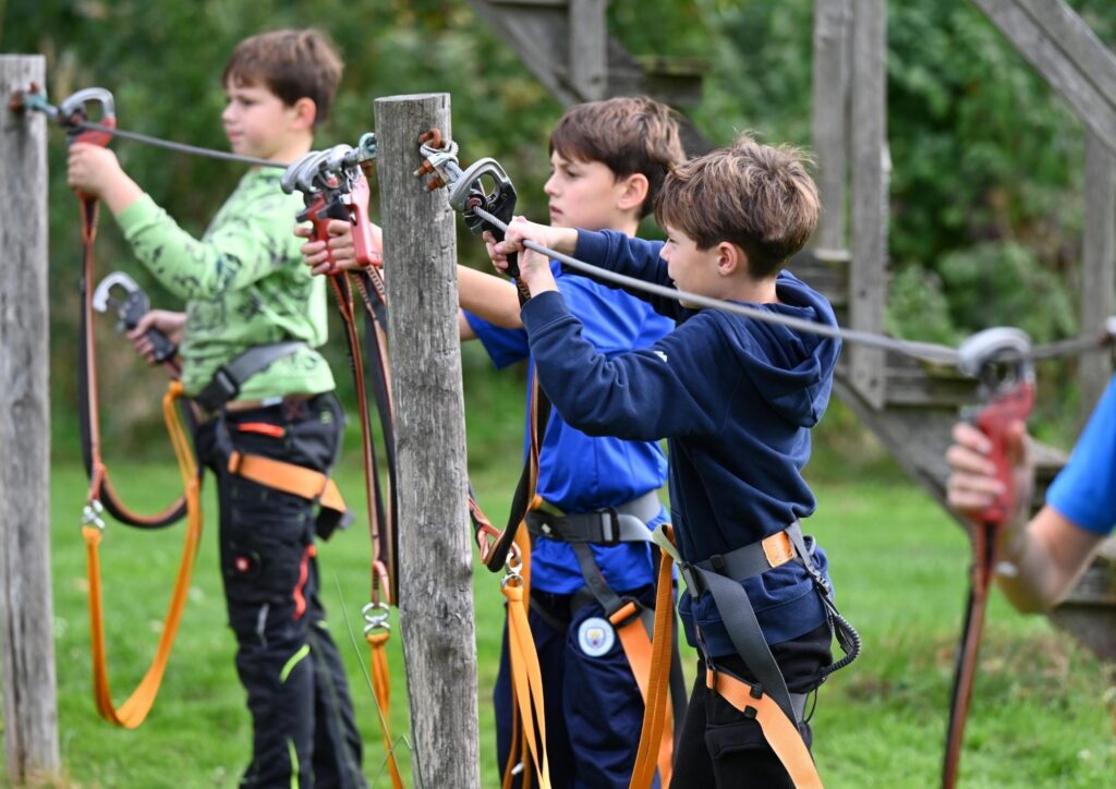 Drie jongens lopen over een touwparcours.